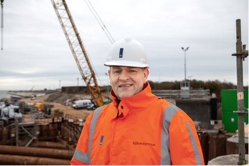 Portret van projectdirecteur in een oranje hesje op een bouwlocatie