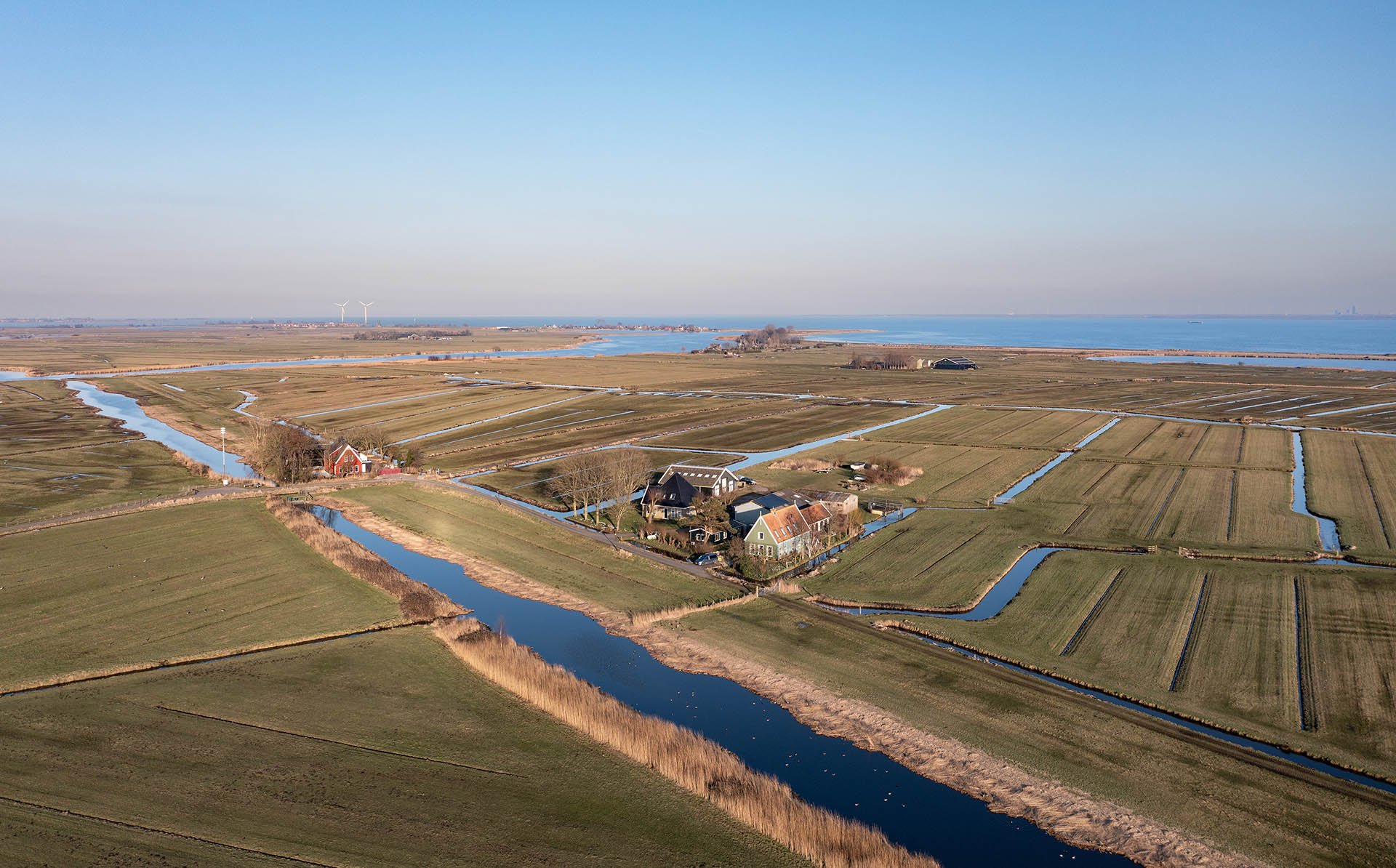 Landschap met boerderij, water en landerijen