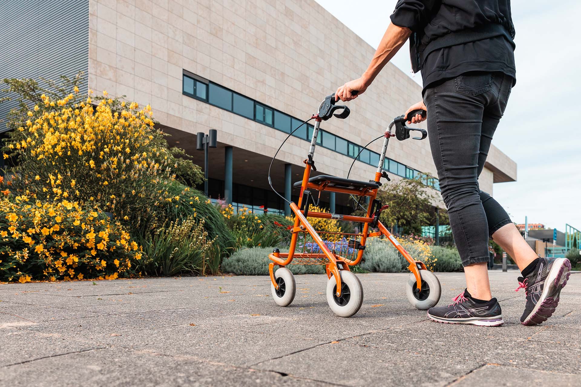 Vrouw met rollater loopt buiten bij een zorginstelling