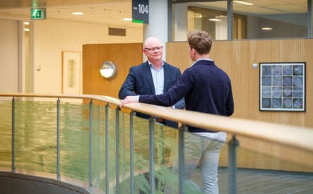 Twee mannelijke collega's voeren gesprek in hal van ziekenhuis