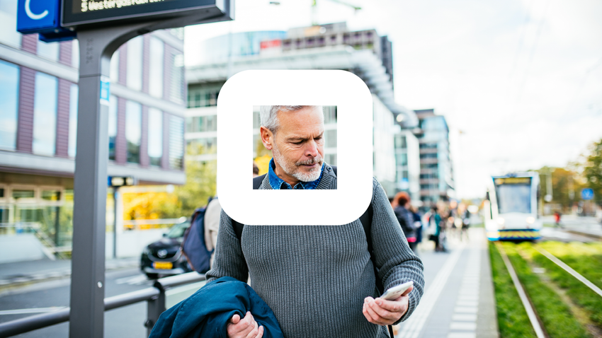 man-loopt-bij-bushalte-en-kijkt-naar-telefoon