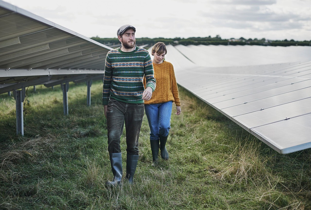 Man en vrouw lopen door zonnepanelen veld